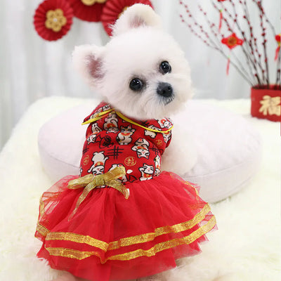 Small white dog wearing red New Year's dress pet sweater with lucky cat print and gold trim tutu skirt