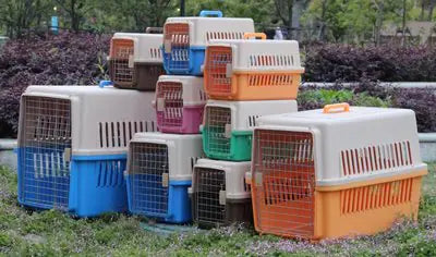 Stack of colorful pet airline carriers for cats and dogs in various sizes outdoors